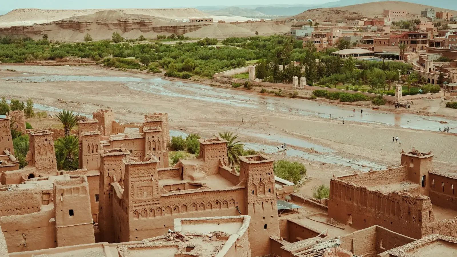 Earthen towers at Ait Benhaddou overlooking the riverbed, palm trees and surrounding hills