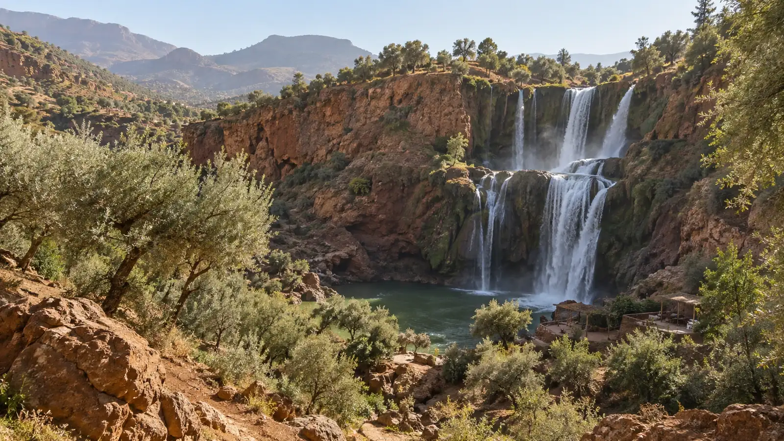 A waterfall dropping into a green pool in a rocky valley